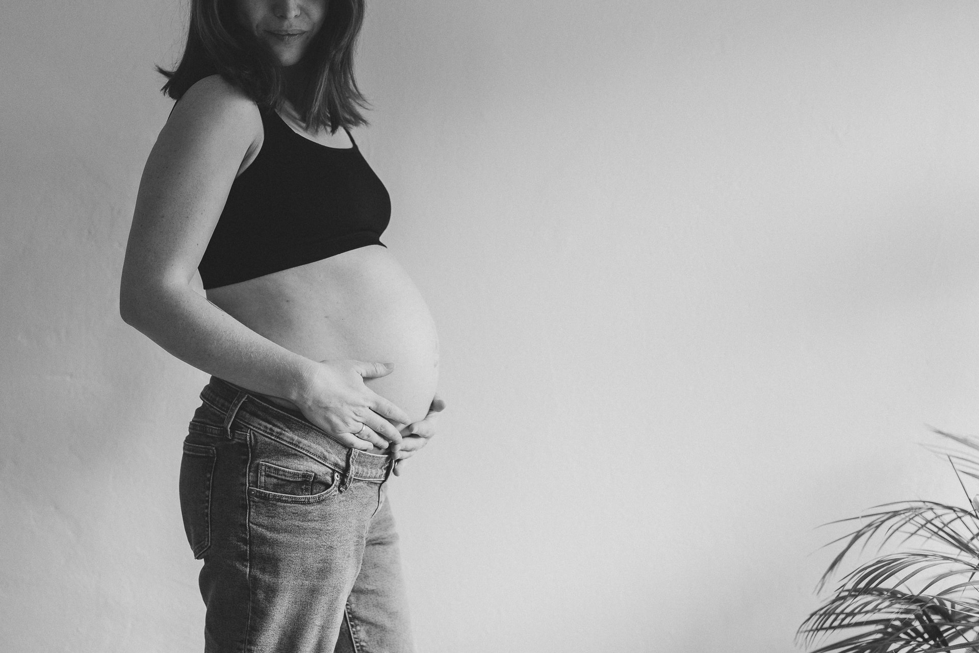 Babybauch Fotografin Ulm, Schwangere hält Bauch mit beiden Händen, schwarz-weiß Portrait