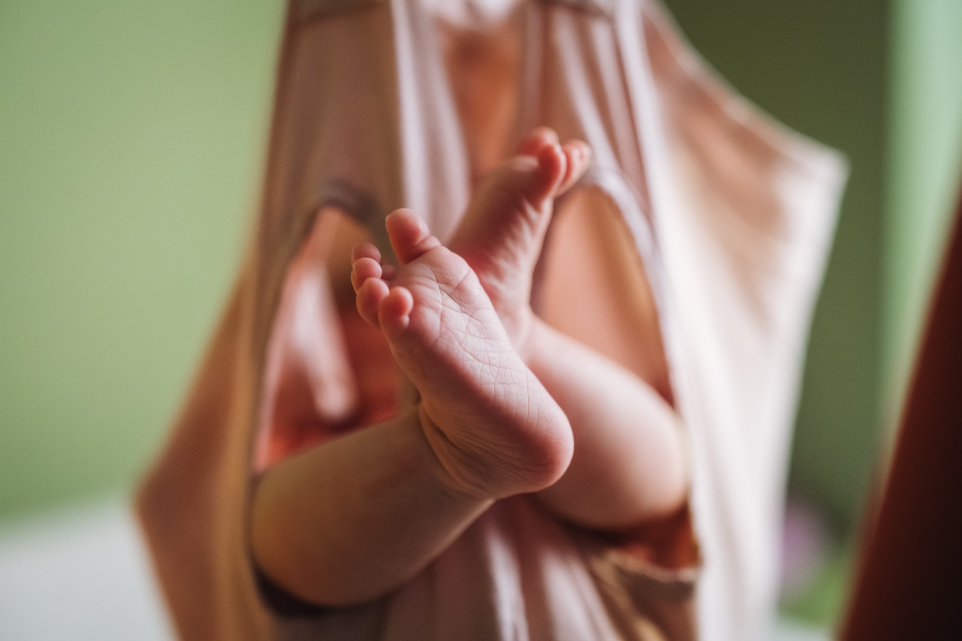 Newborn Fotografie Ulm, Babyfüße Nahaufnahme im Tragetuch, Geburtshaus