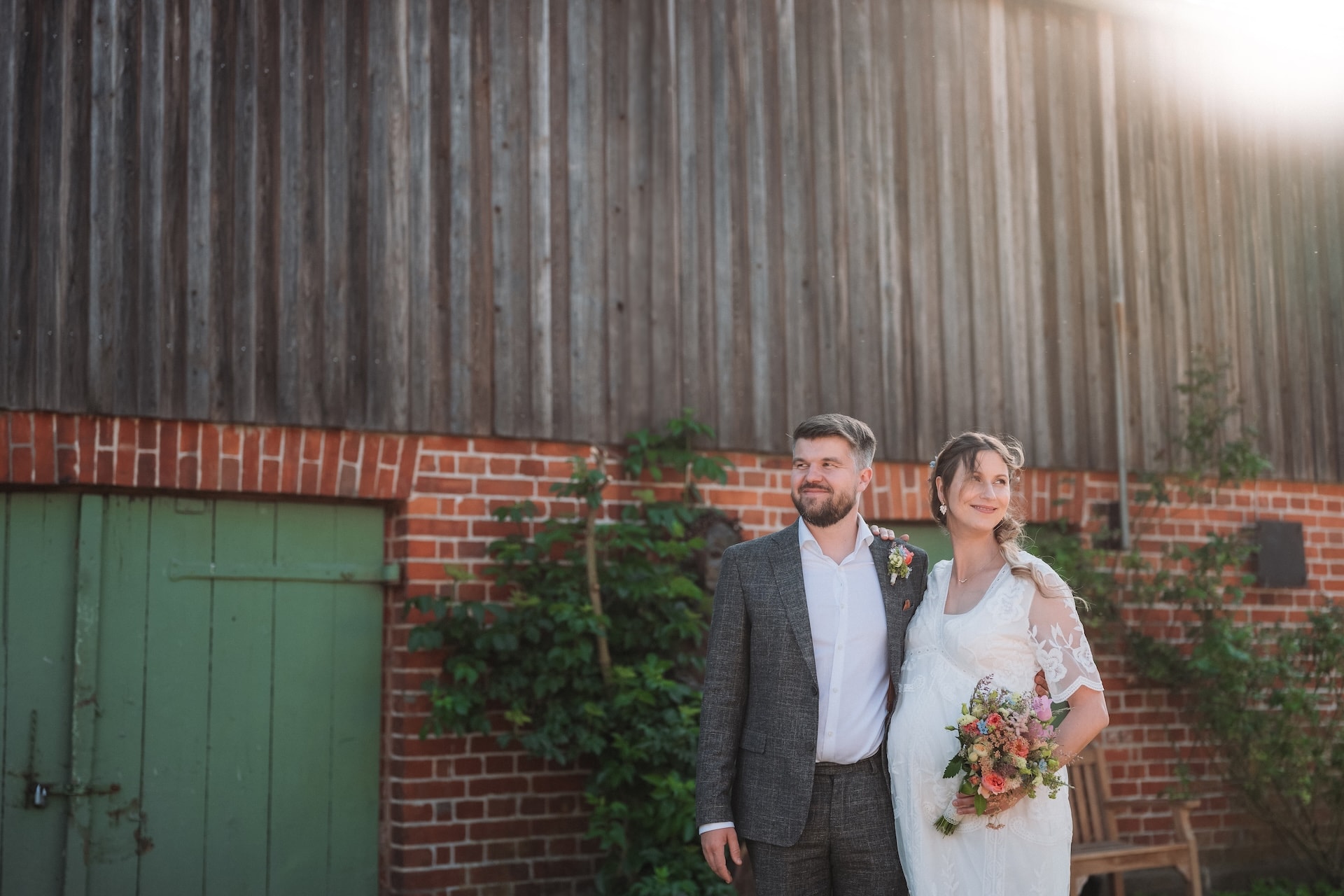 Hochzeitsfotografie Lübeck, Brautpaar vor alter Backsteinscheune im Gegenlicht, Scheunenhochzeit Lübeck