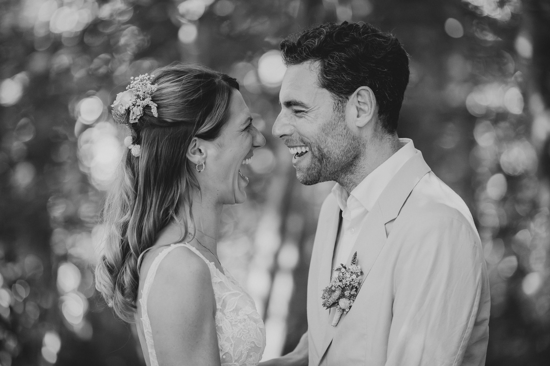 Hochzeitsfotografie Ulm, Braut und Bräutigam lachen sich herzlich an, Schwarzweißportrait mit Bokeh im Hintergrund