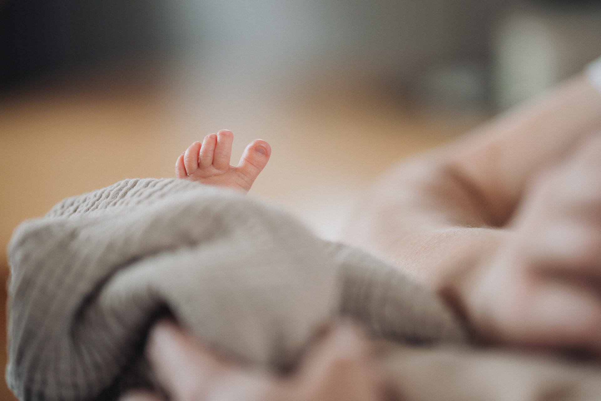 Newborn Fotografin Ulm, winzige Babyfüße ragen aus Strampler, natürliches Licht Detail